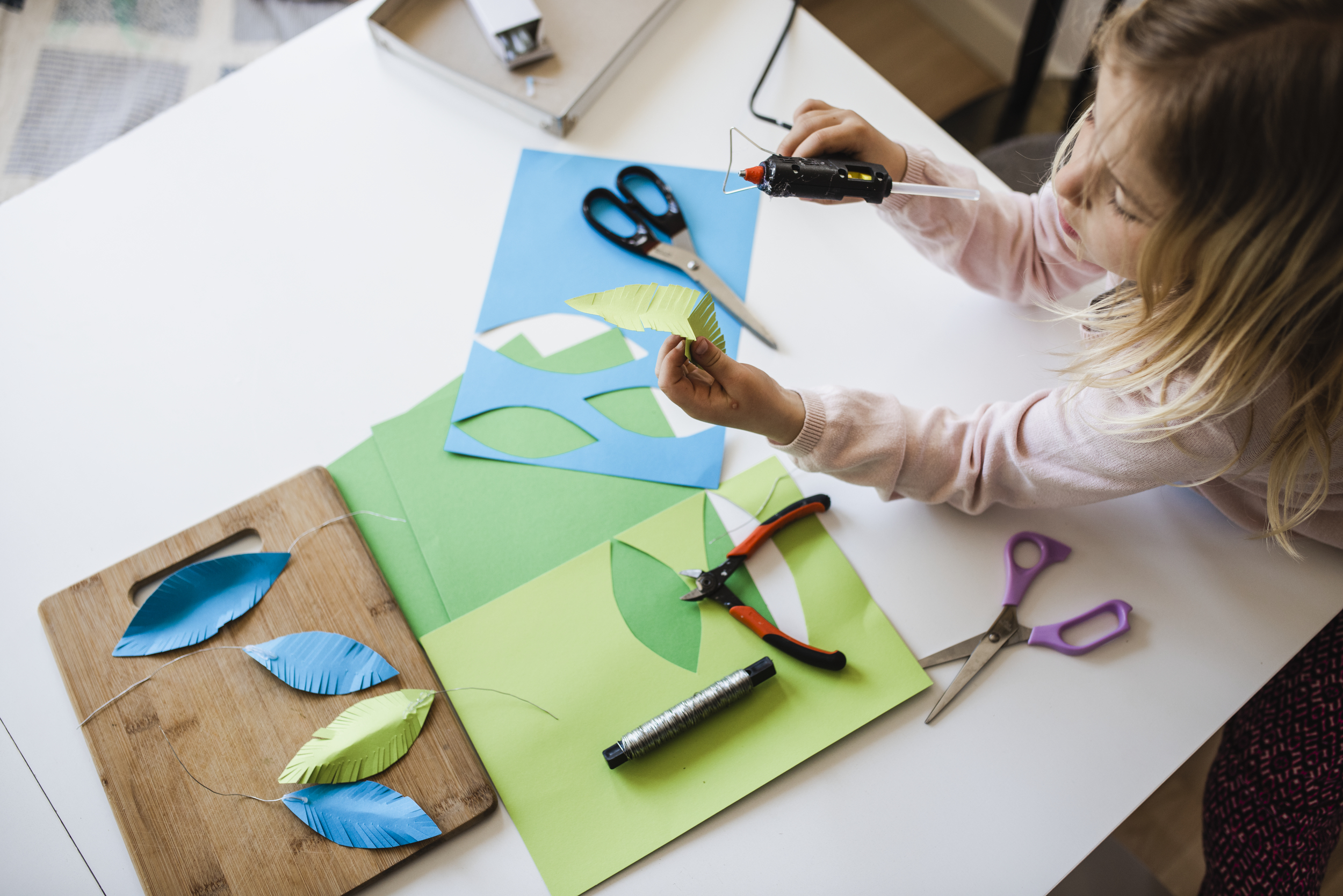 Flicka som klipper löv i papper